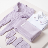 Nesta imagem, é possível explorar outros ângulos do kit de saída de maternidade. A tonalidade lilás é uma tendência que traz harmonia e suavidade para o visual da bebê.
