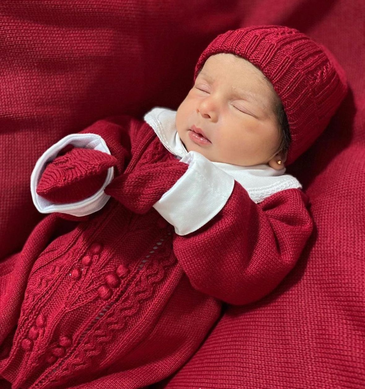 A foto mostra a bebê dormindo confortavelmente, vestindo o kit que a deixa ainda mais linda.  