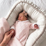 A foto mostra a bebê dormindo confortavelmente, vestindo o kit que a deixa ainda mais linda.